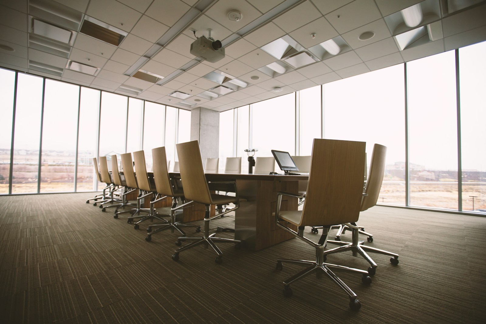 An empty conference table by a window, set for a meeting that has not begun.